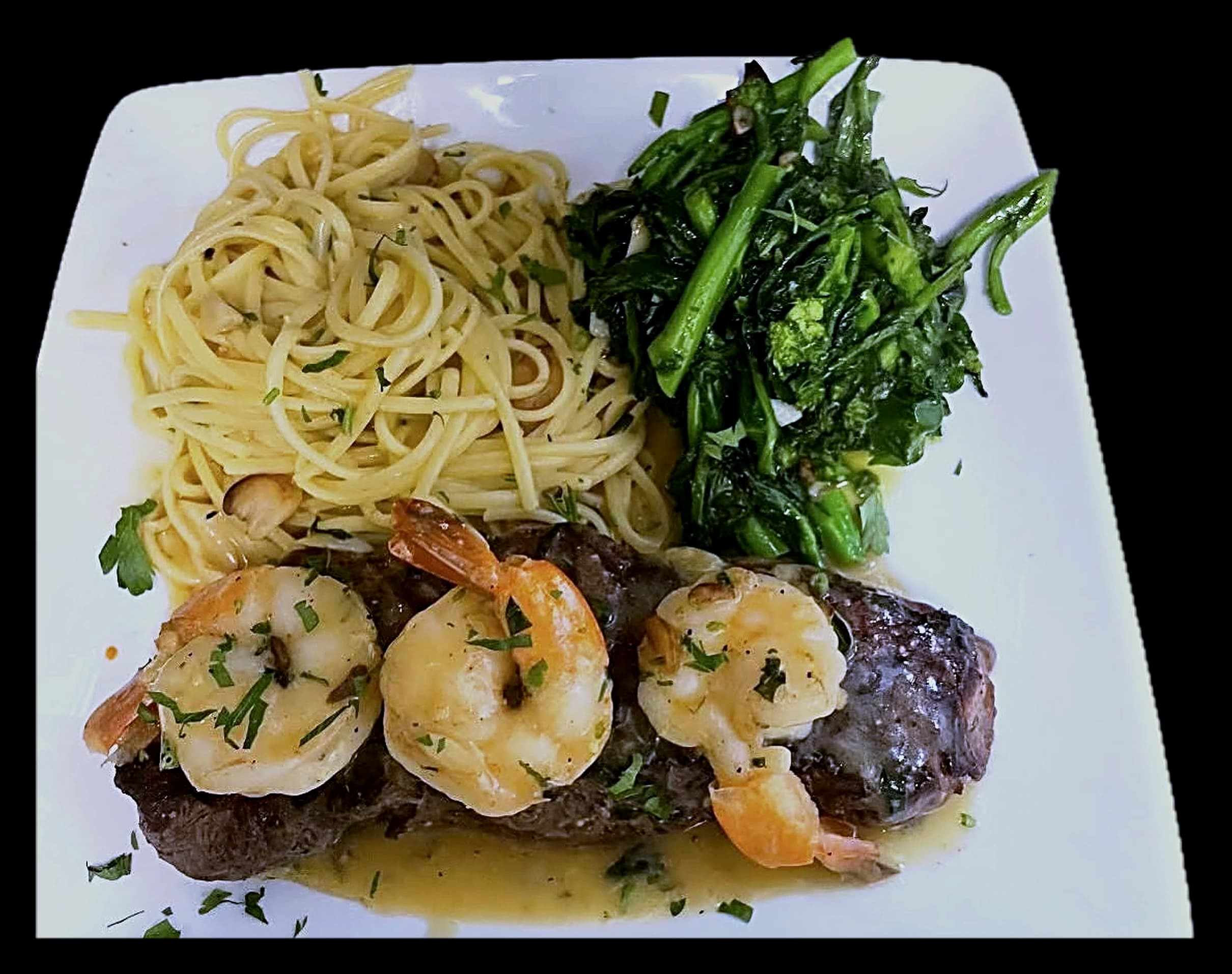 NY strip steak topped with shrimp scampi, linguine aglio e olio, and broccoli rabe